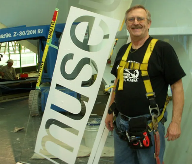 Dave Detary on a lift installing a large etched glass sign on site